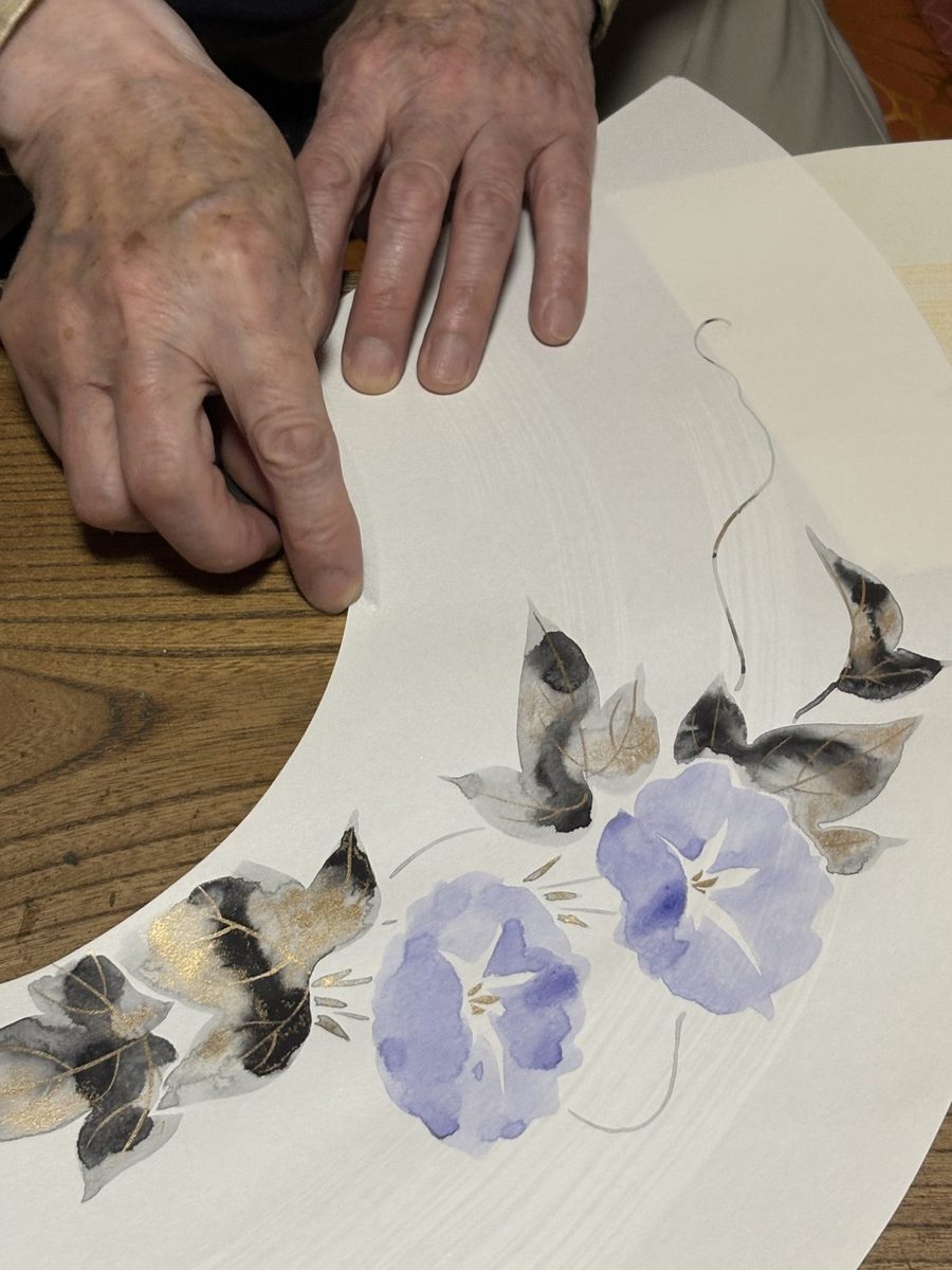 朝顔が描かれた扇面と、それを押さえる職人の手